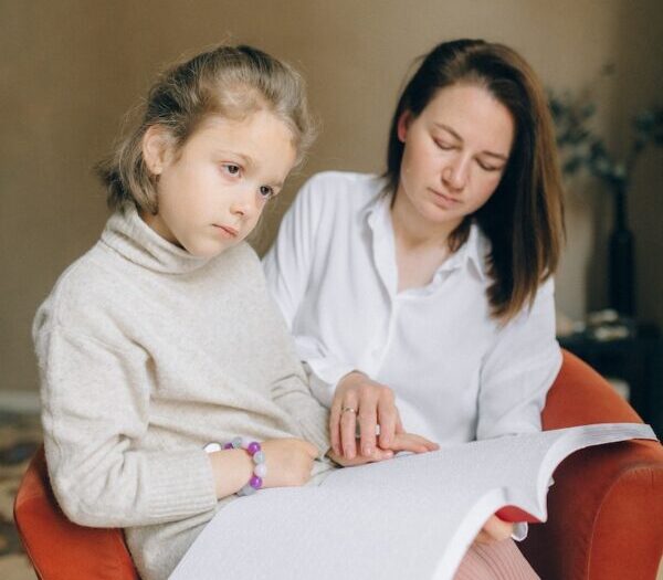 A Woman Teaching a Girl to Read Braille Book